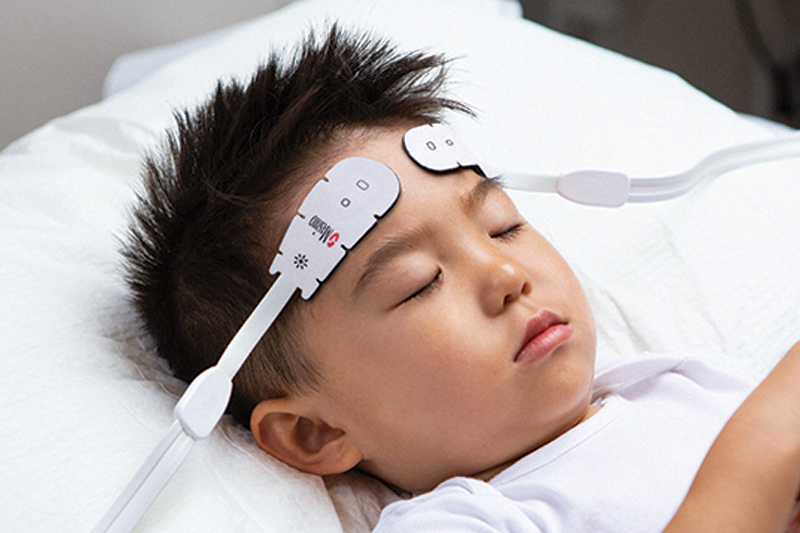 Sleeping patient intubated in hospital bed being monitored with Masimo sensor.